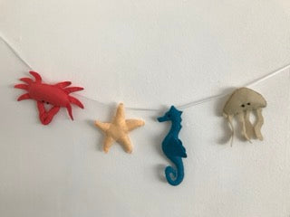 Handmade padded Felt Sea Creature Garland threaded on a ribbon string. A seahorse, crab, starfish and a jelly fish all brightly coloured.