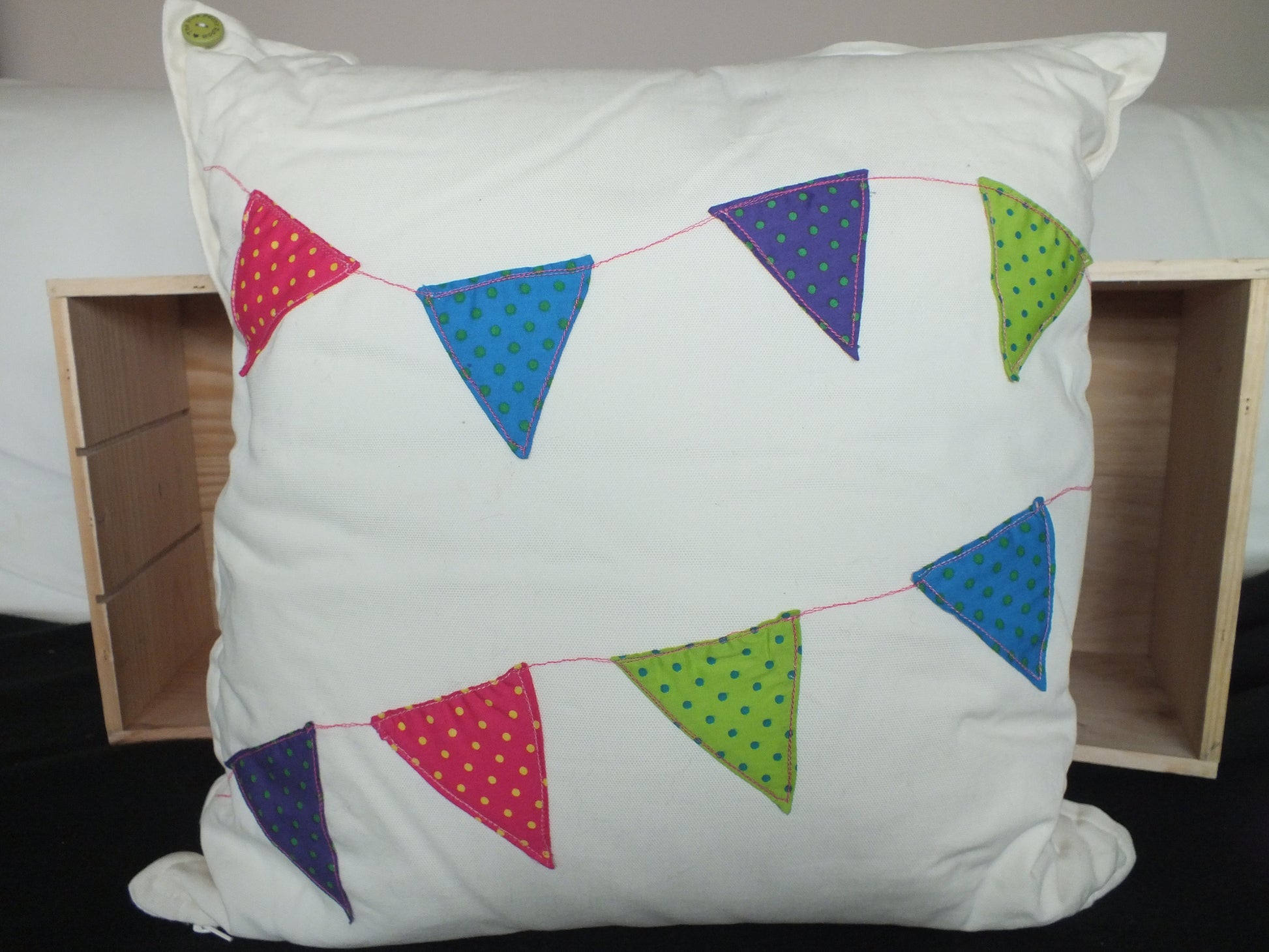 Hand sewn Bunting Cushion, this square cushion has a colourful mini bunting stitched on the front and makes a perfect gift for a child’s bedrooms.