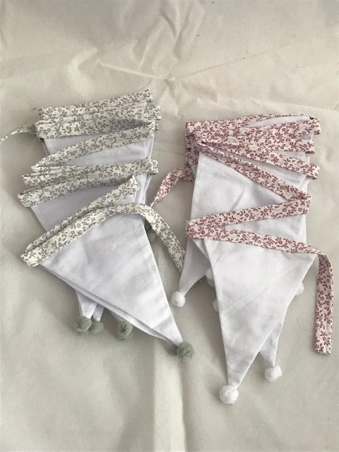 Handmade White Cotton Pom-Pom Bunting.    Perfect for hanging in your child&#39;s room or baby nursery.  They have 17 flags measuring approximately 2.2 metres. Available in maroon floral binding and grey floral binding.